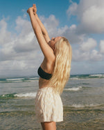 Cream-colored textured shorts with wavy pattern detail worn on a beach.