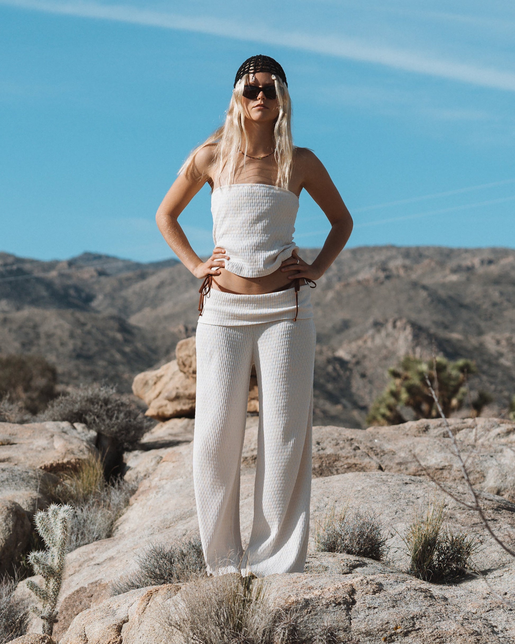 White ribbed tube top and matching pants worn with sunglasses and white cap.