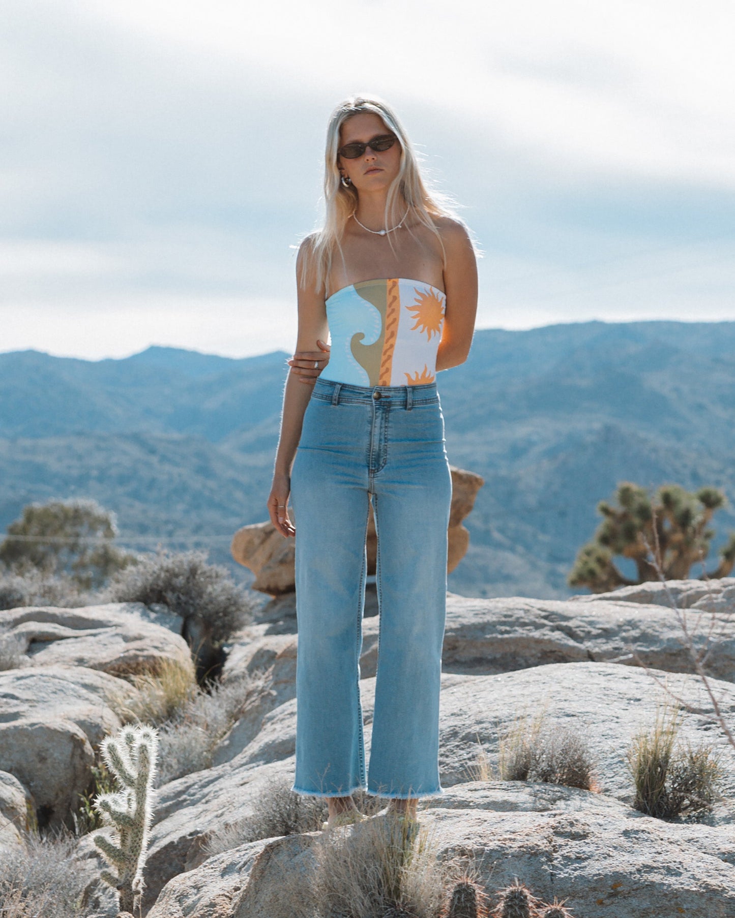 Light blue high-waist denim pants with raw hem, worn with patterned crop top.
