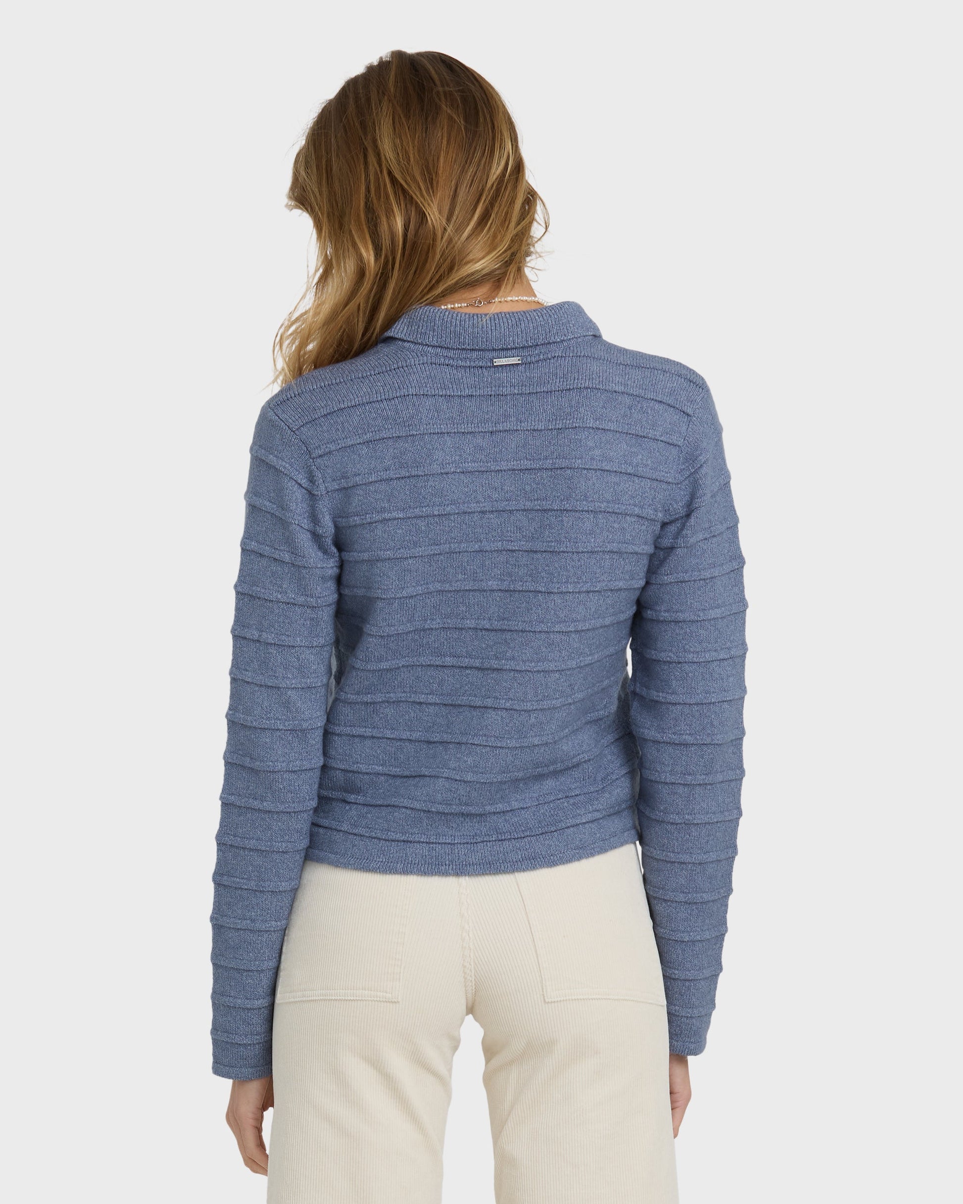 Stone blue ribbed knit sweater with crew neckline, shown from back on model wearing cream pants.