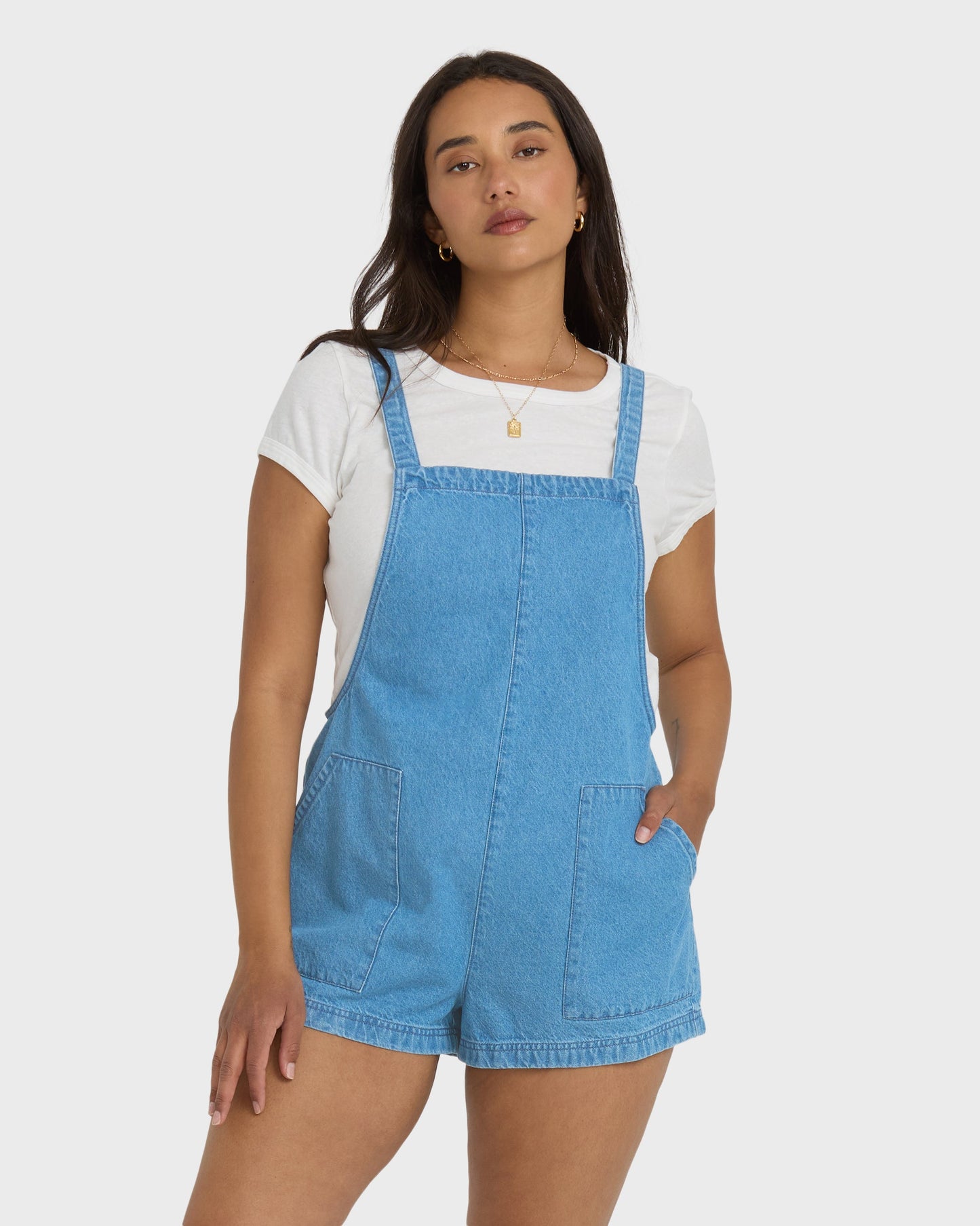 Light wash denim shortalls with adjustable straps and front pockets, worn over a white short-sleeve shirt.