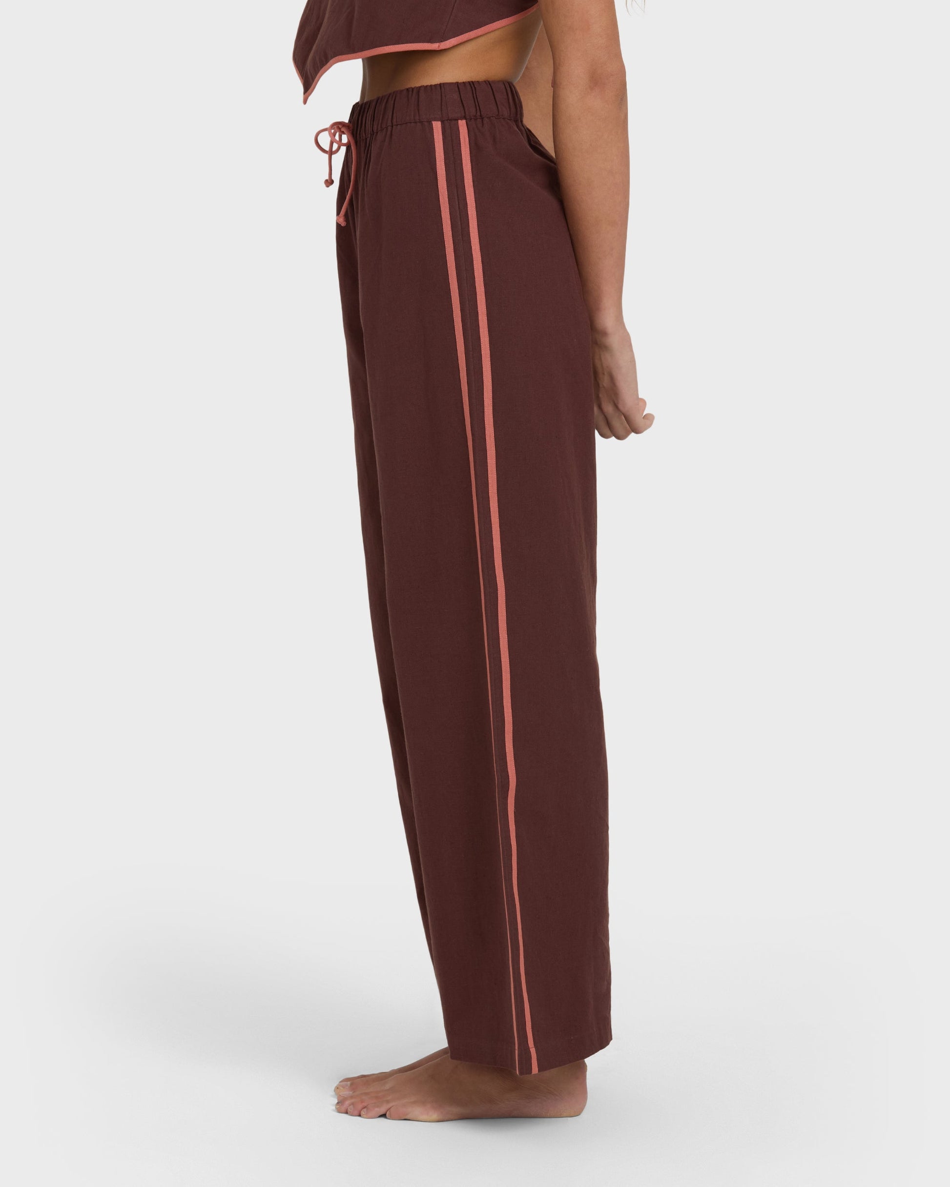 Teak elastic waist pants with coral side stripes and drawstring, shown on model from waist down.