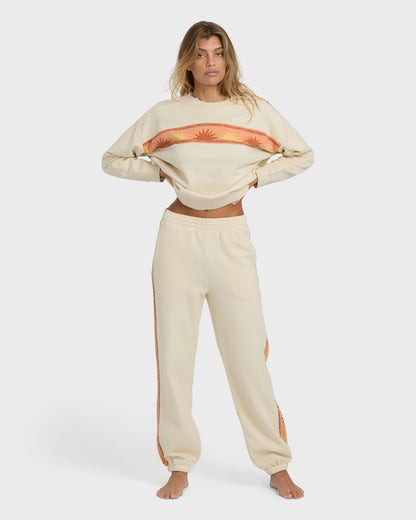 Cream-colored cropped sweatshirt and joggers set with orange sun stripe design on chest and side panels.
