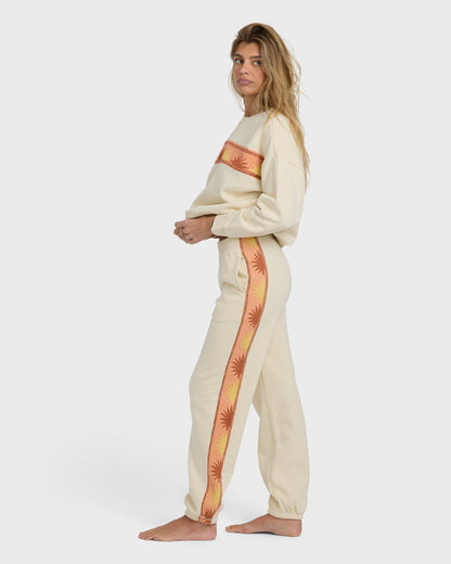 Cream-colored jogger set with coral and yellow palm-print side stripe on sweatshirt and pants.