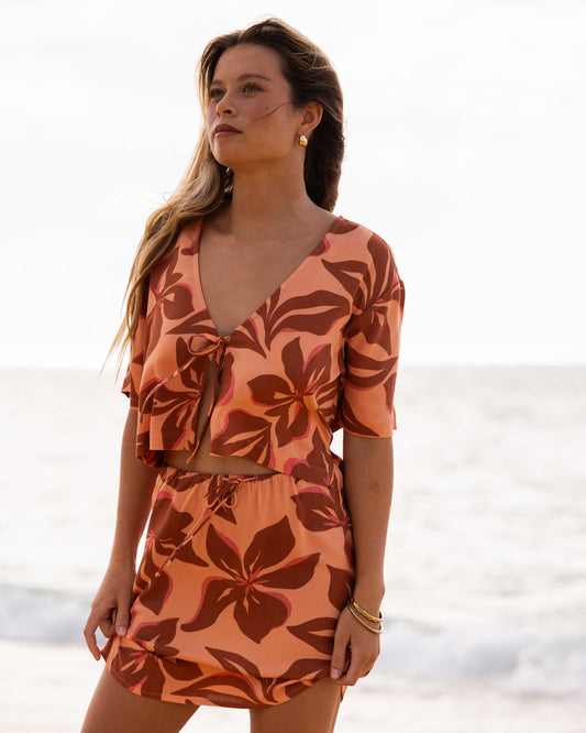 Apricot wrap dress with brown and red sunflower print, short sleeves, and drawstring waist.