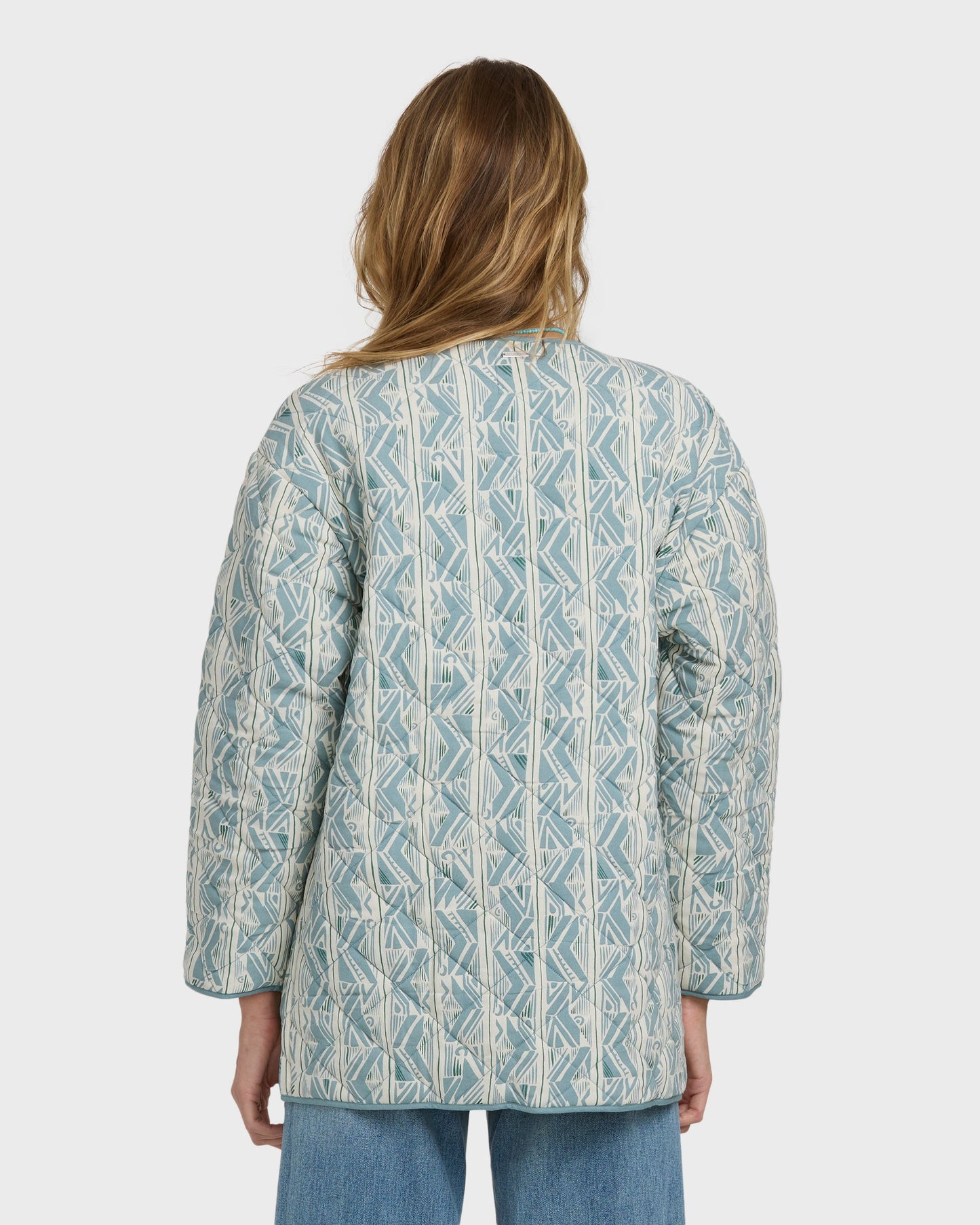Mineral blue quilted jacket with geometric pattern worn over jeans, shown from back view.