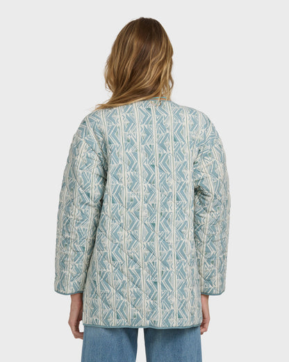 Mineral blue quilted jacket with geometric pattern worn over jeans, shown from back view.