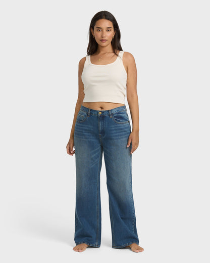 Faded blue denim straight leg pants with vintage wash worn with white tank top.