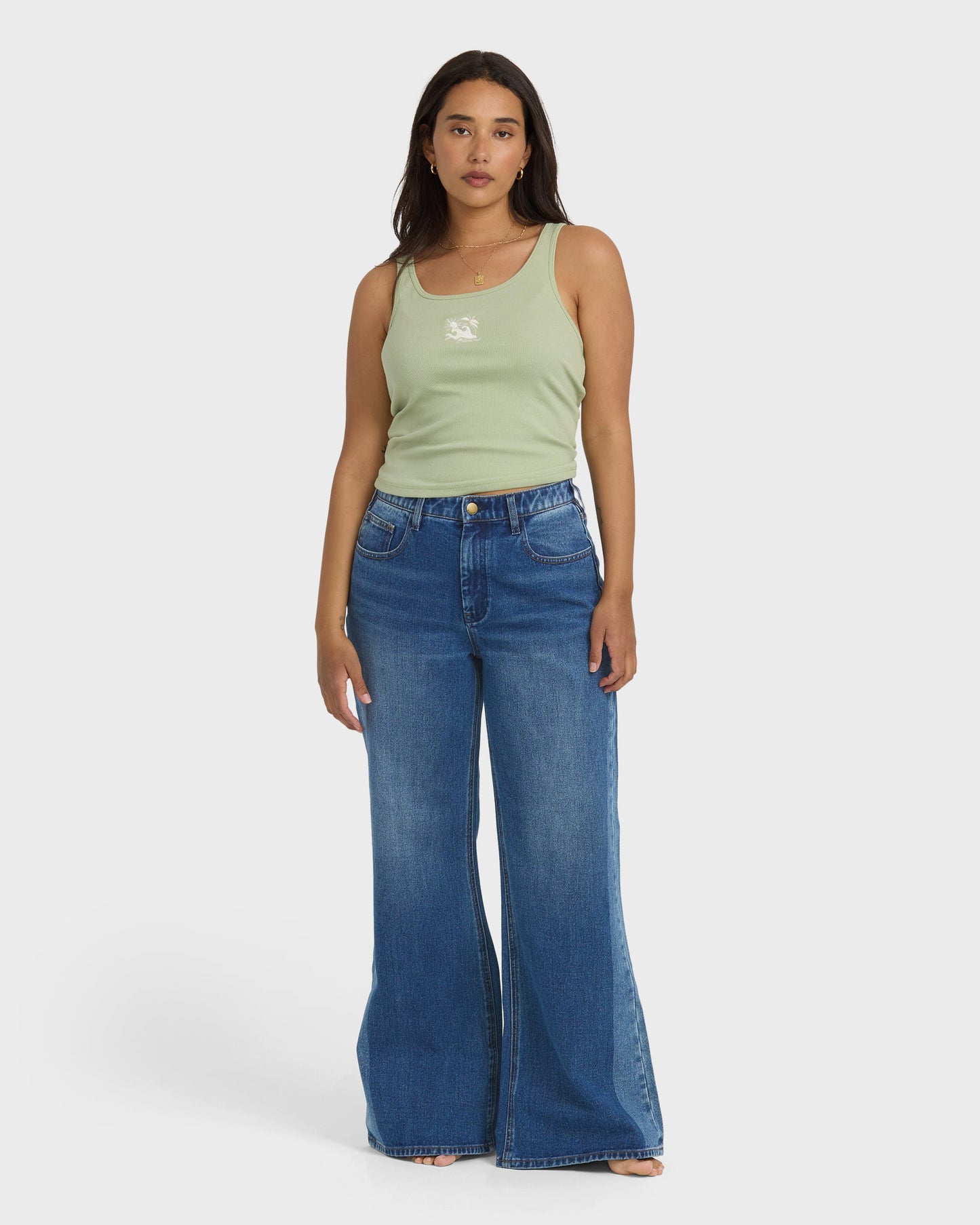 High-waist blue denim flare pants with distressed details, styled with a sage green tank top.