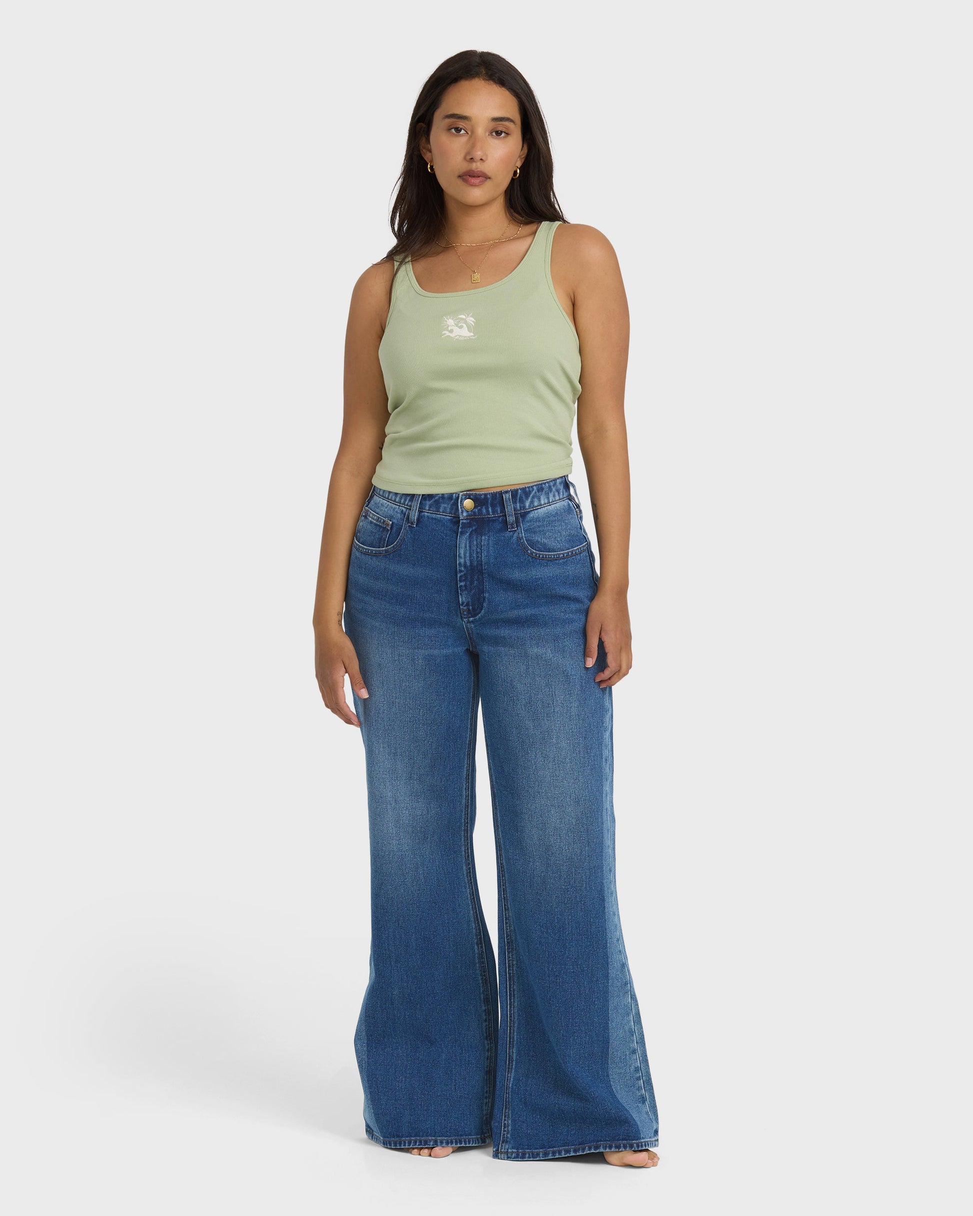 High-waist blue denim flare pants with distressed details, styled with a sage green tank top.