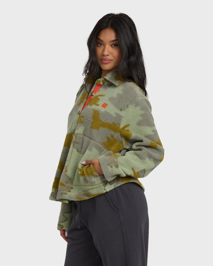 Camouflage sherpa shacket in sage and gold tones with button front and collar, paired with black pants.