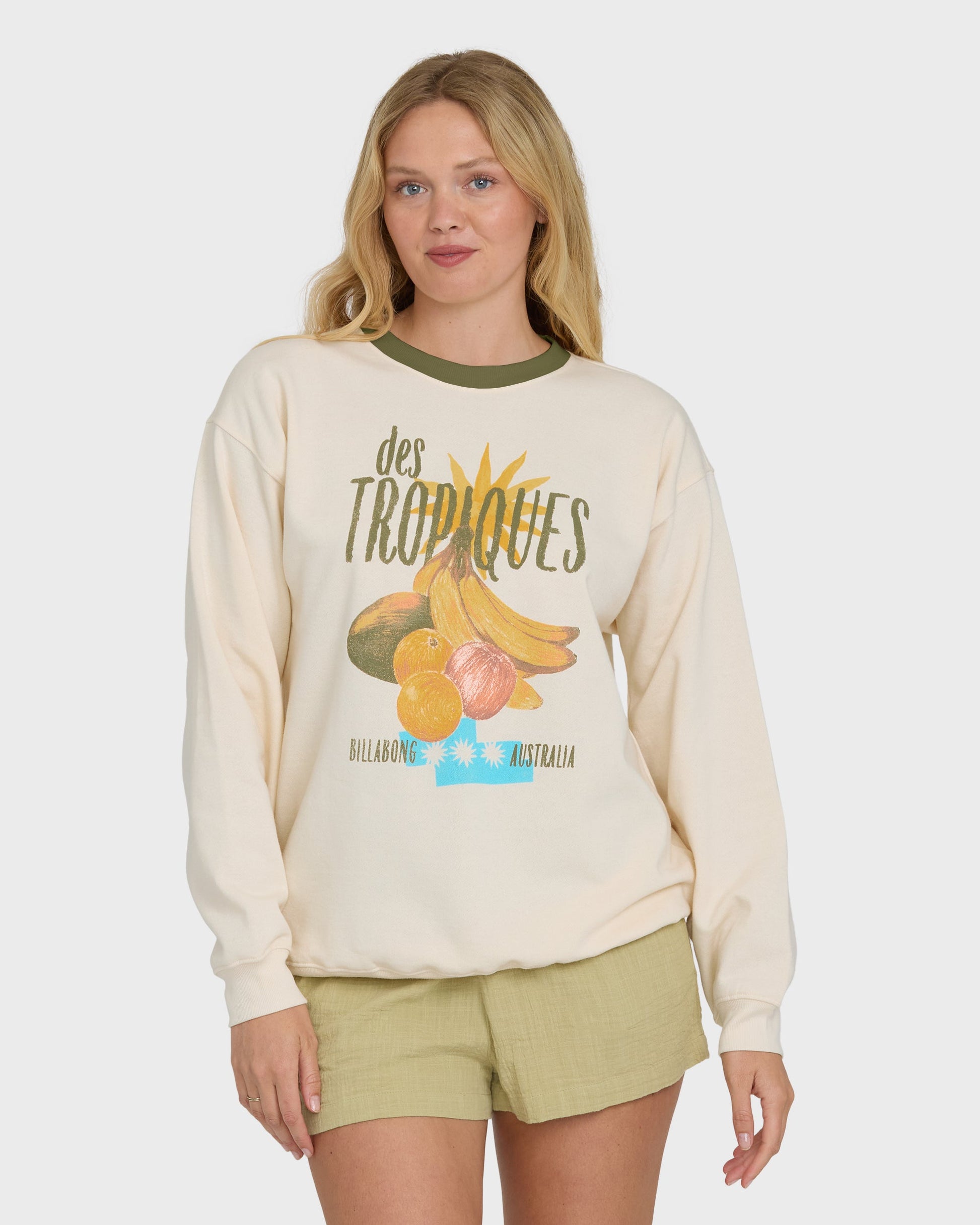 Cream crewneck sweatshirt with tropical fruit graphic and "des Tropiques" text, worn with olive green shorts.
