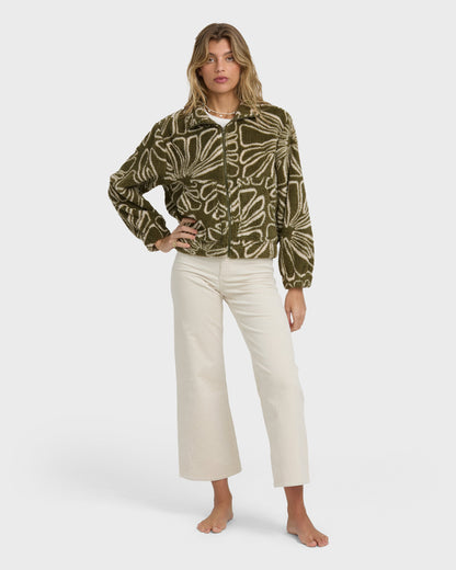Olive and cream sherpa fleece jacket with abstract line pattern and front zip closure, worn with cream pants.