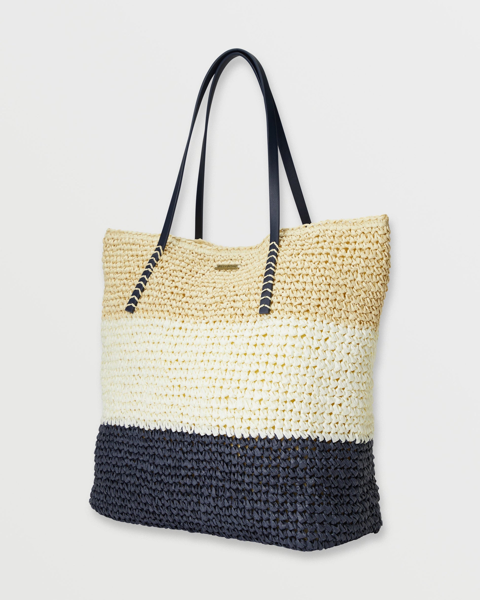 Woven straw tote bag with colorblock design in natural, cream, and black sections with dark shoulder handles.