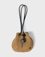 Tan woven straw mini tote bag with black crossbody straps and palm tree charm detail.