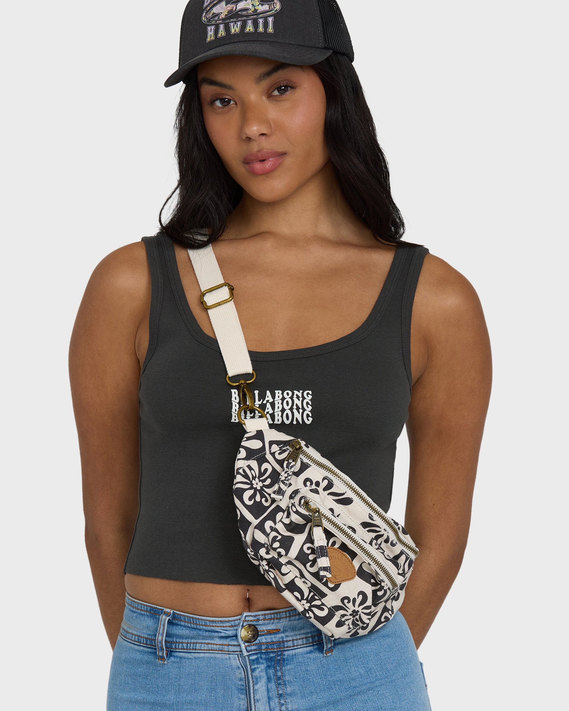 Black and white patterned waistbag with cream shoulder strap and gold hardware, worn across torso.