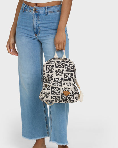 Black and white floral patterned mini backpack with tan leather accent held by person in blue jeans.