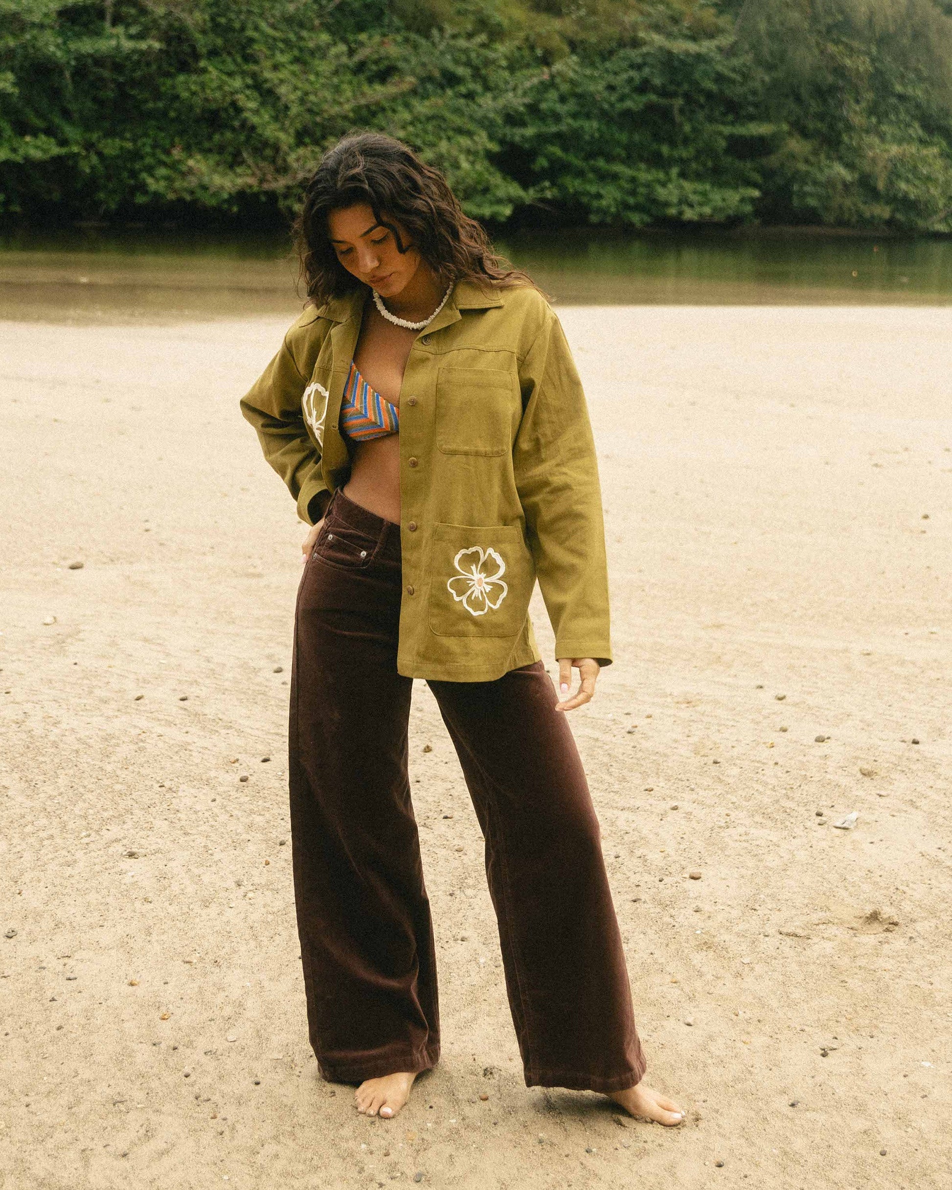 Brown corduroy wide-leg pants styled with a yellow-green jacket on a person standing on a beach.