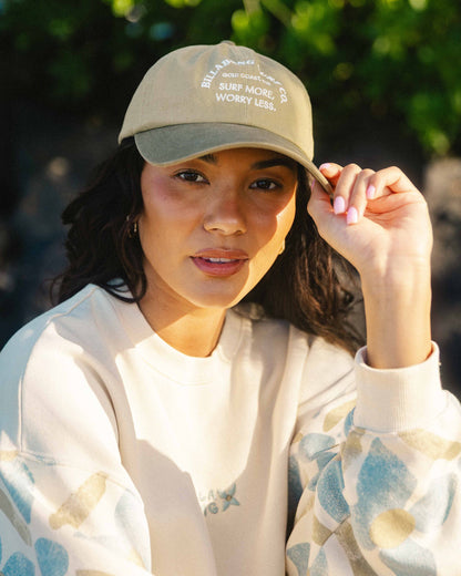 Beige and gray dad cap with white embroidered text on crown, worn by person outdoors.