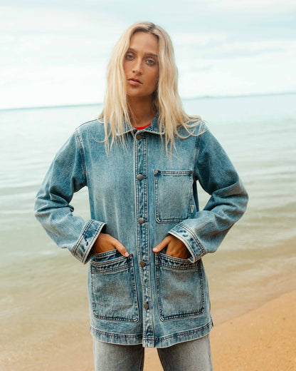 Medium-wash denim chore coat with chest and front patch pockets, button front, and rolled cuffs.