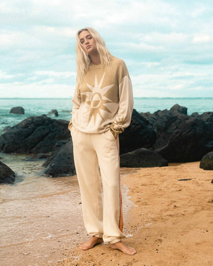Cream-colored sweater with sun graphic on chest, worn with matching pants.