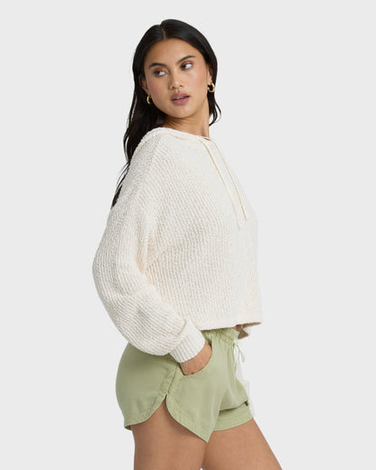 Avocado green shorts with elastic waist and front pockets, paired with cream ribbed sweater.