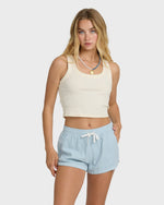Light blue chambray shorts with elastic waist and drawstring tie, worn with cream ribbed tank top.