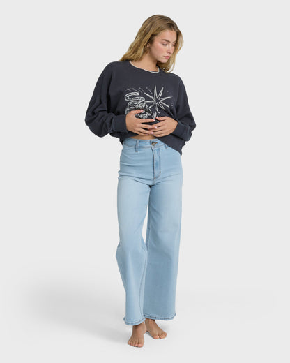 Light blue high-waist denim pants with straight leg fit, worn with black graphic sweatshirt.