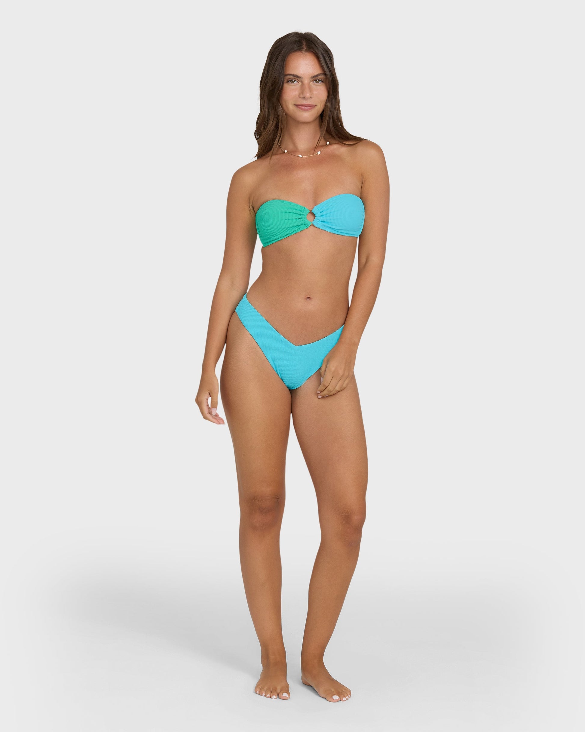 Bandeau bikini top in teal and turquoise color block with center knot detail, shown on model with matching bottoms.