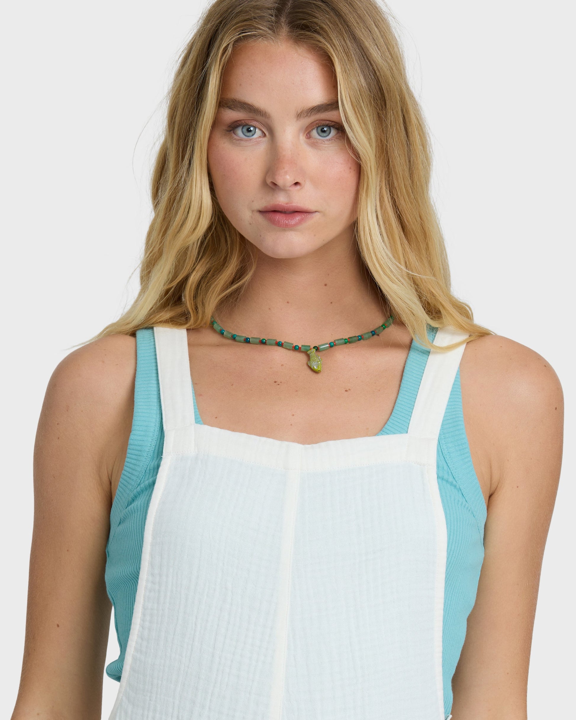 Woman wearing a sleeveless romper with white center panel, turquoise side panels, and square neckline.