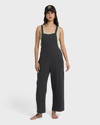 Black sleeveless jumpsuit with square neckline and cream-colored side panels, shown on model.
