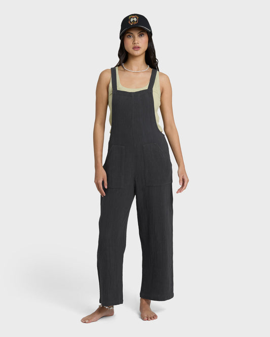 Black sleeveless jumpsuit with square neckline and cream-colored side panels, shown on model.