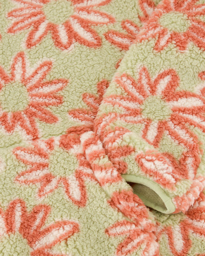 Close-up of a textured fabric with pink floral patterns on a green background
