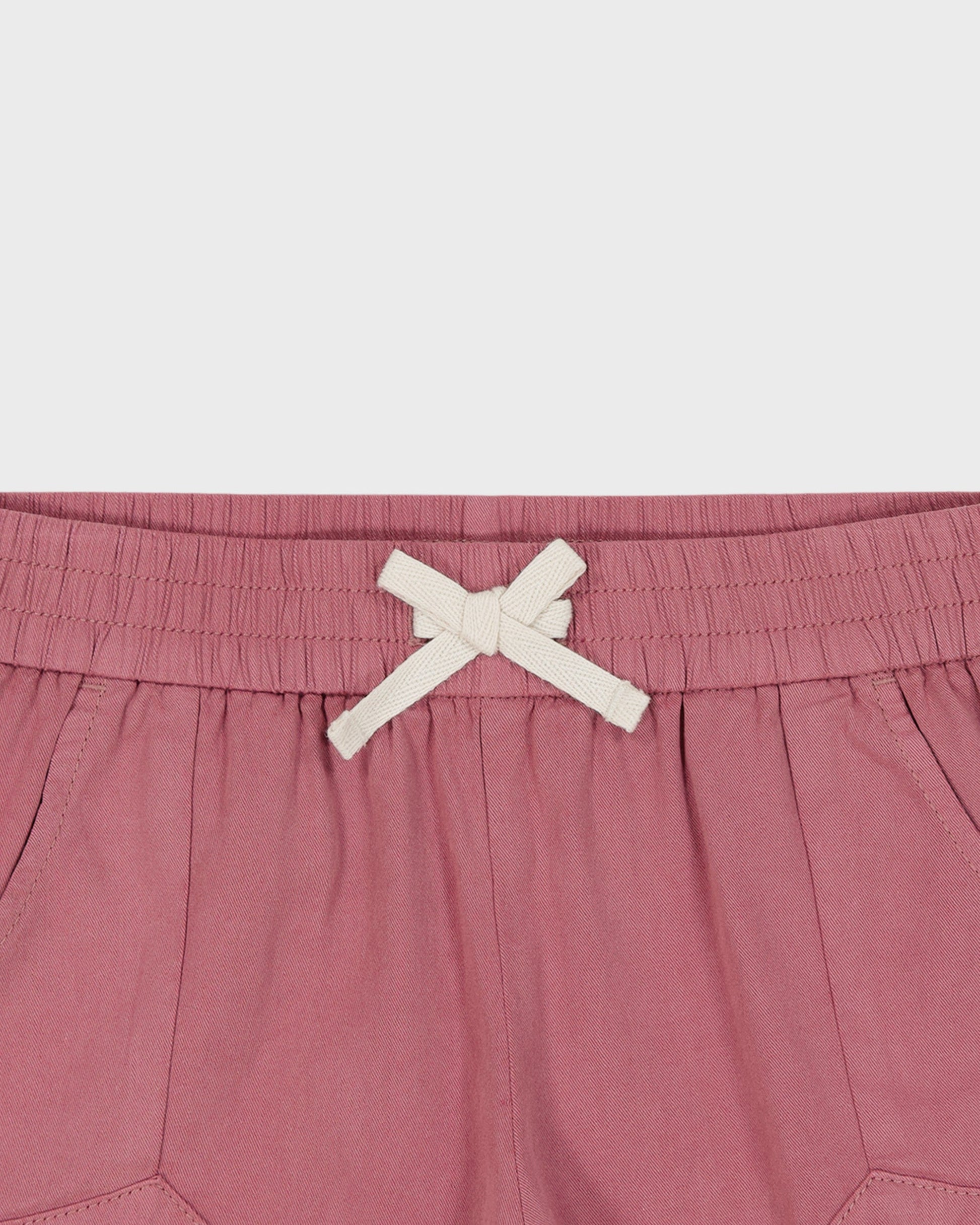 Pink shorts with a white drawstring on a light gray background