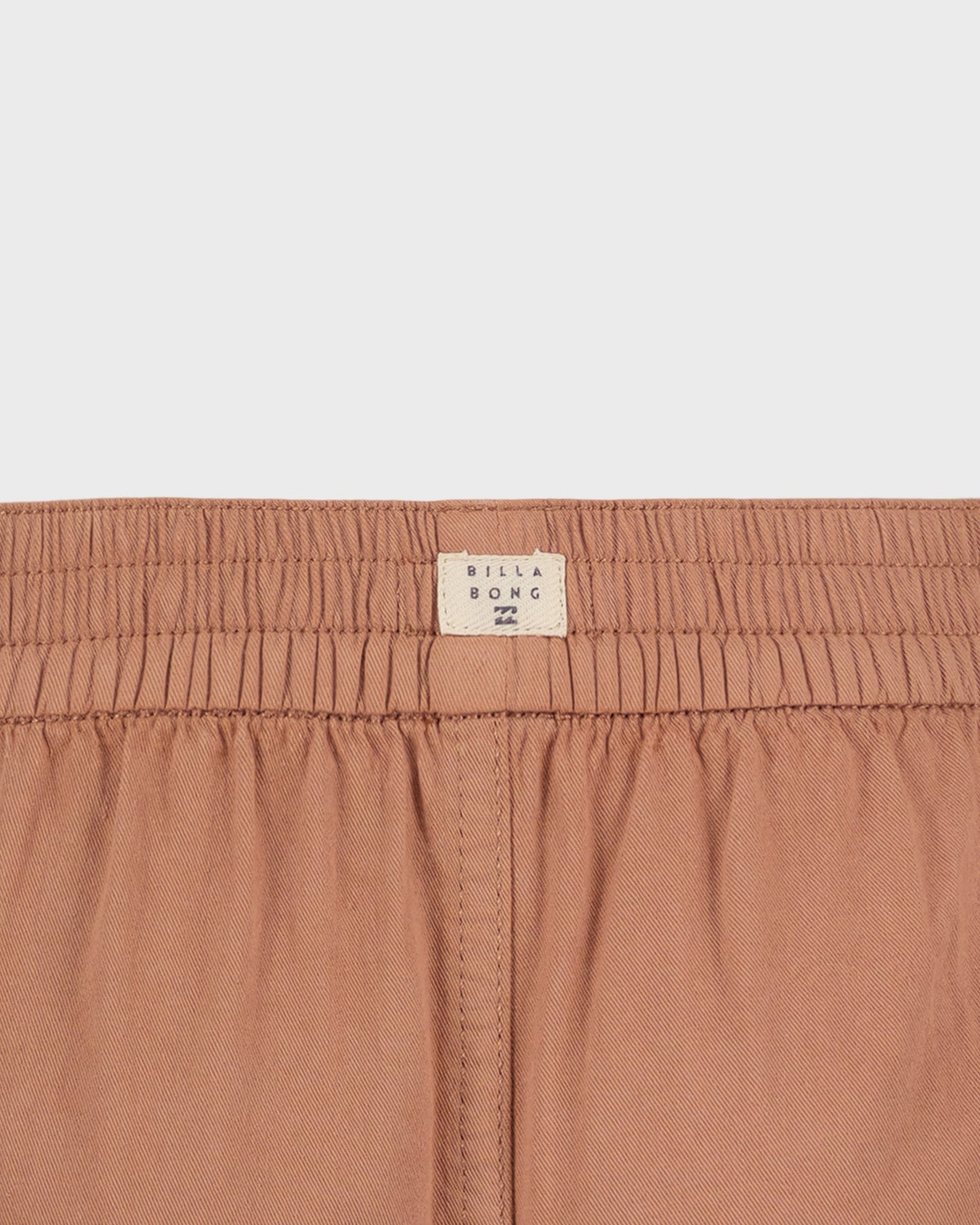 Close-up of a brown garment with a visible brand label on a light gray background