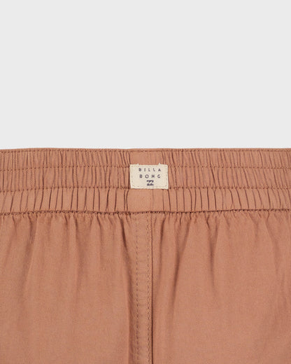 Close-up of a brown garment with a visible brand label on a light gray background