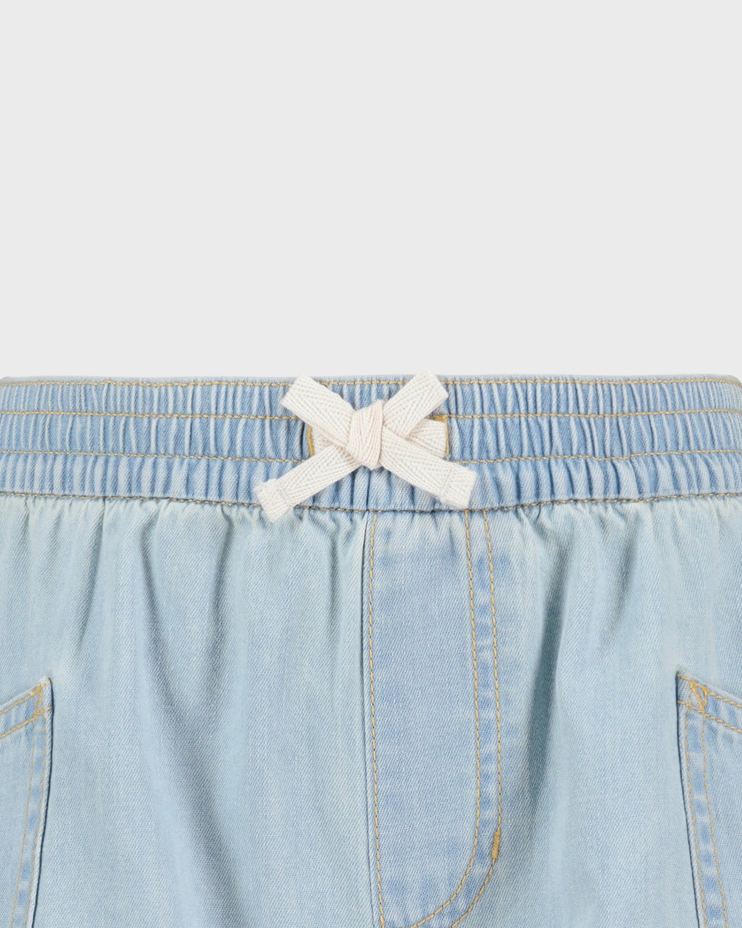 Light blue denim shorts with a white bow on a light gray background