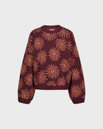 Maroon sweater with sun pattern on a light gray background