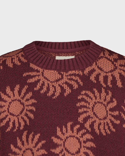 Maroon sweater with sun pattern on a light gray background