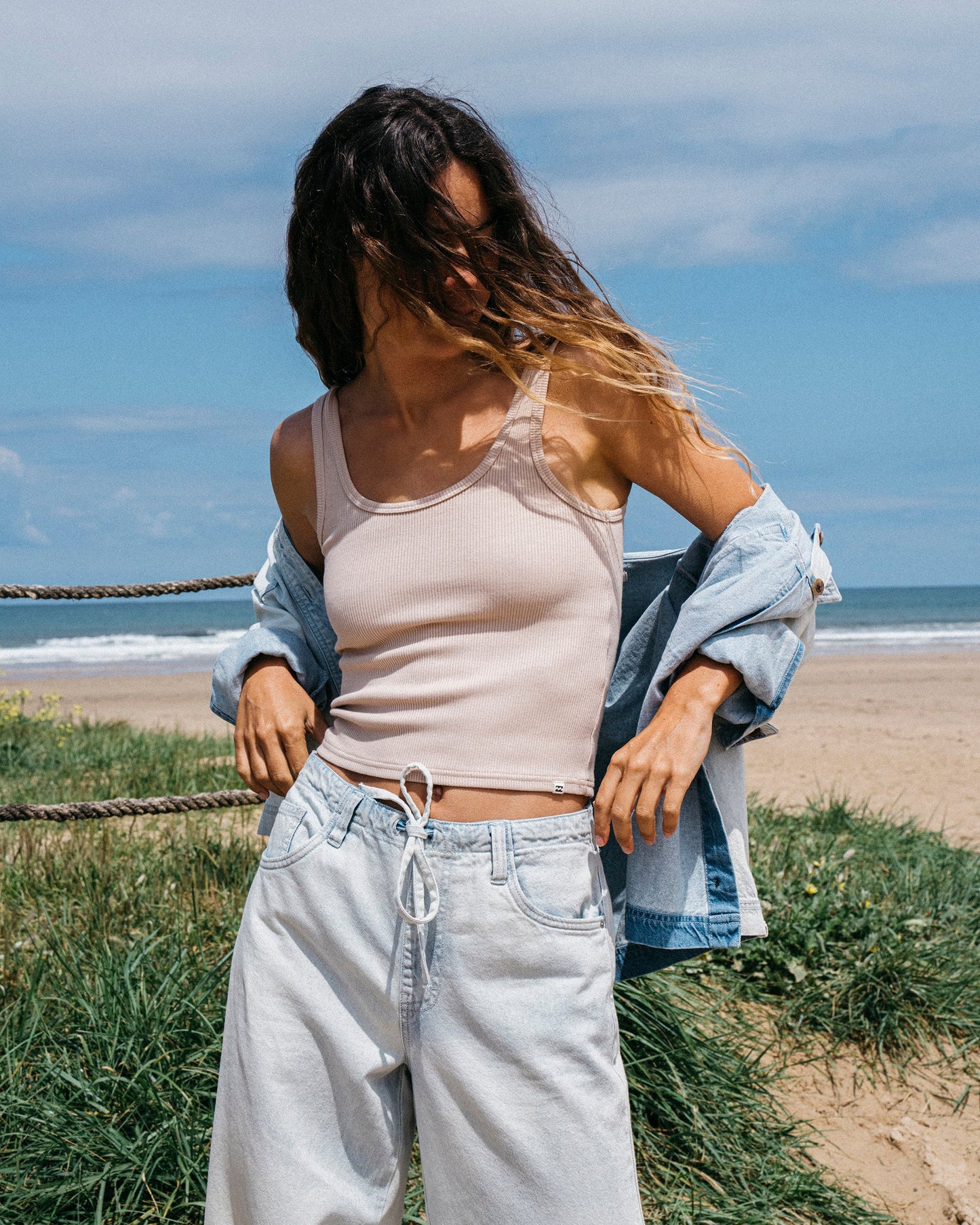 Light blue relaxed-fit pants with drawstring waist worn on model at beach.