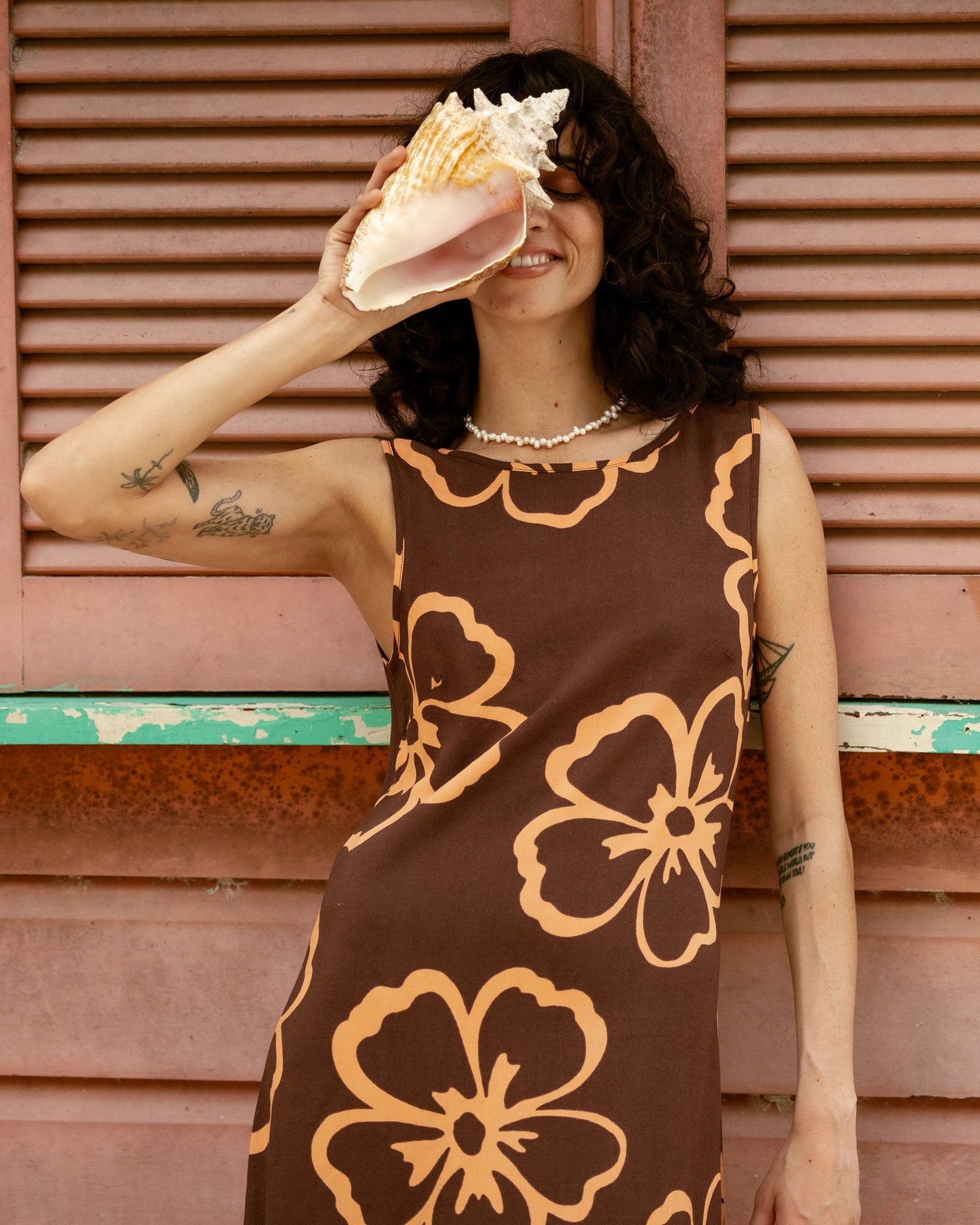 Brown sleeveless dress with large yellow floral print and scalloped neckline.