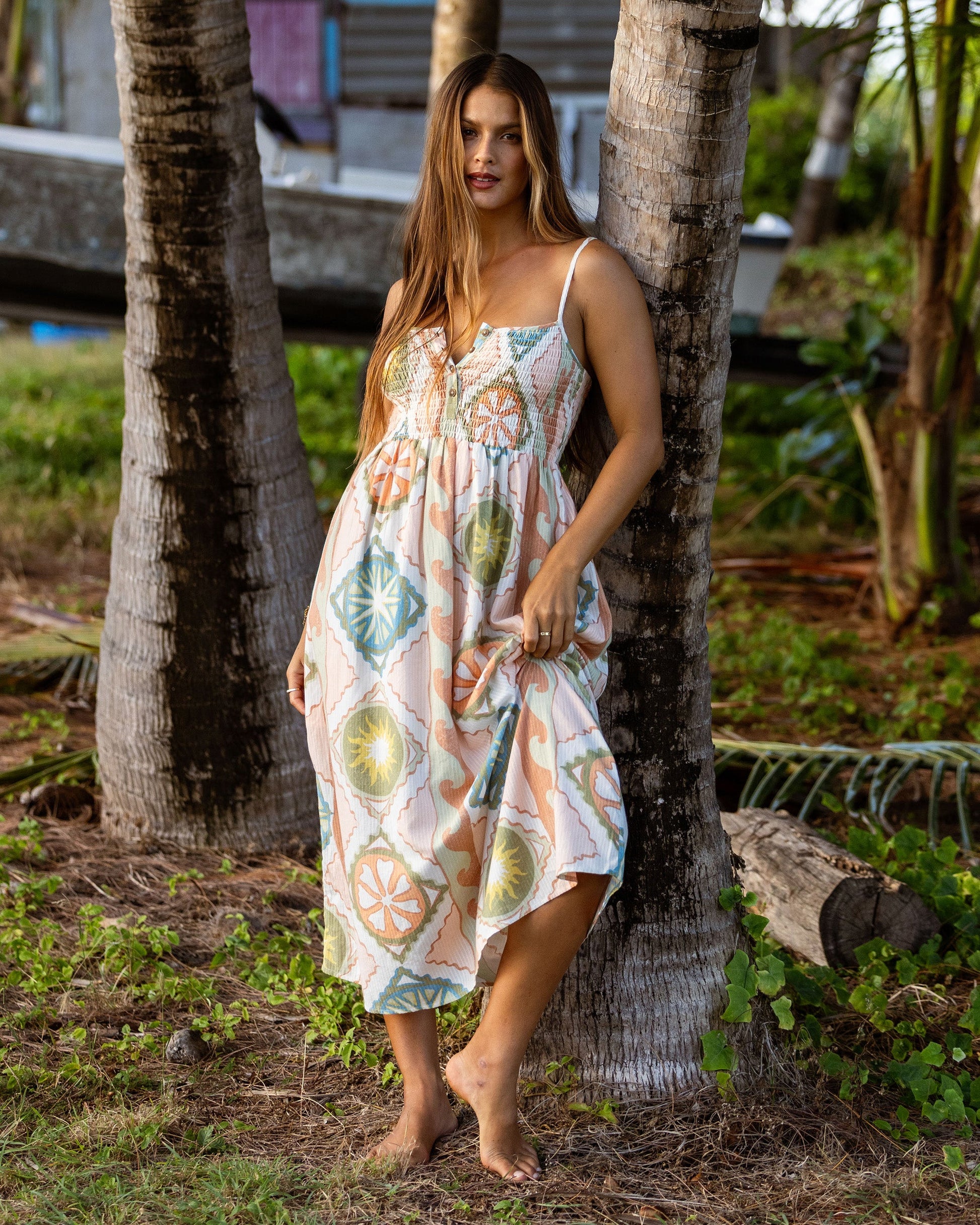 White midi dress with colorful fruit and geometric print, adjustable straps, and gathered bodice.