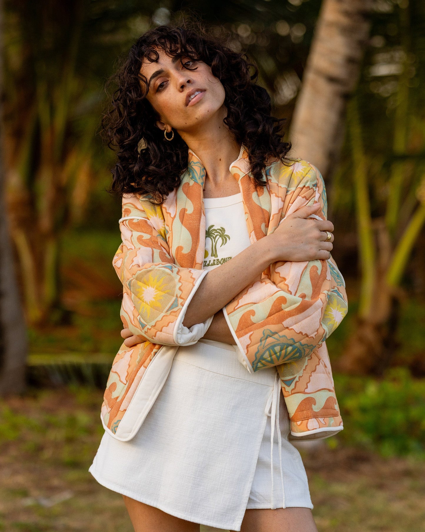 Sand quilted jacket with orange and yellow floral pattern, worn open over white shirt.