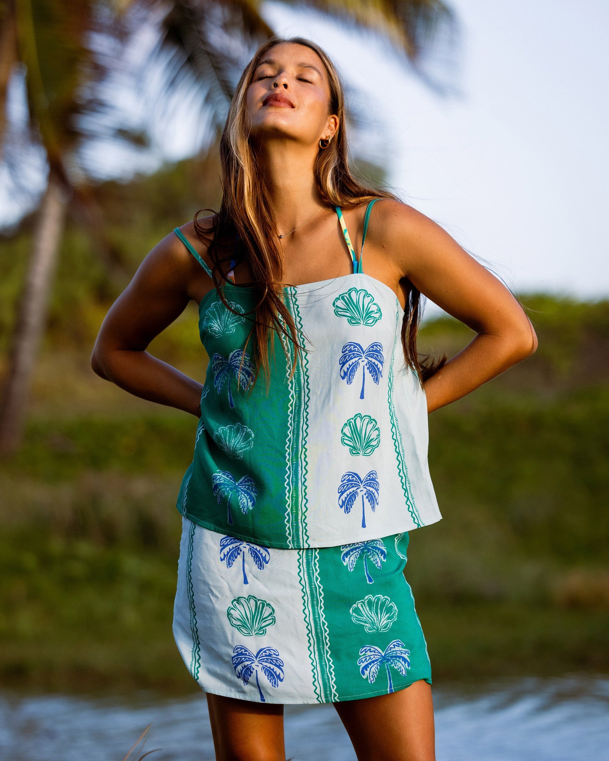 Pool blue and white woven tank top with shell and palm tree print, adjustable straps, worn with matching skirt.