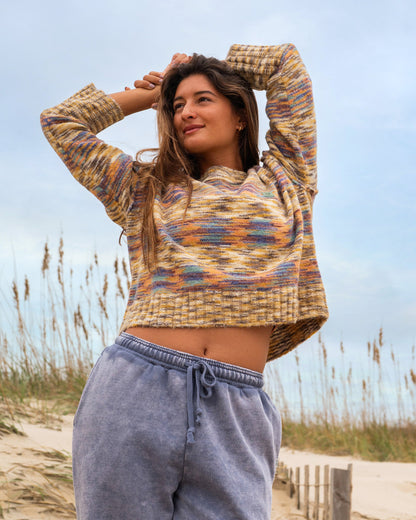 Teak-colored knit sweater with multicolor striped pattern and ribbed texture, worn with blue drawstring pants.