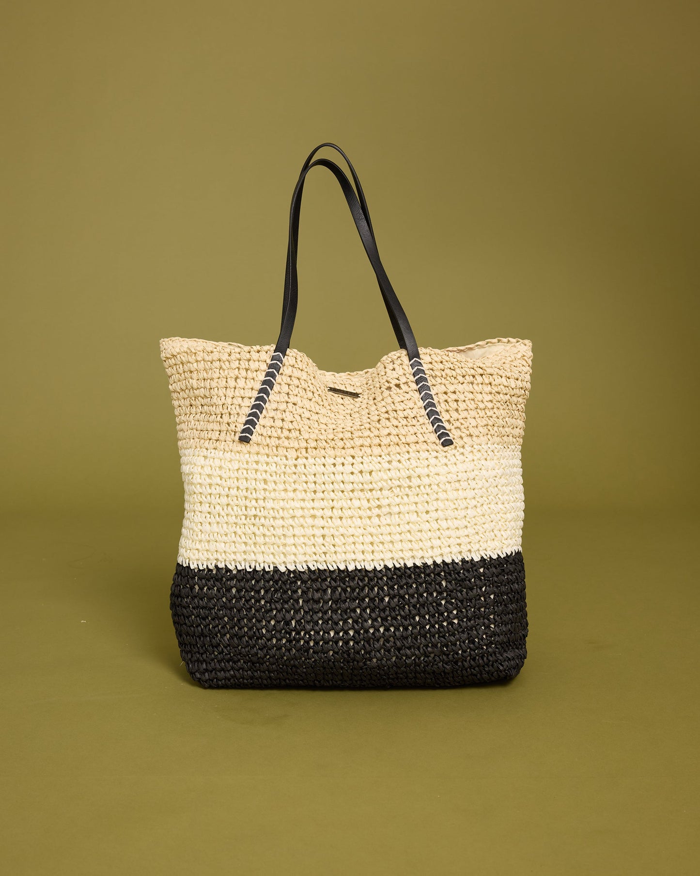Woven tote bag with natural straw upper half, black woven lower half, and black rope handles.
